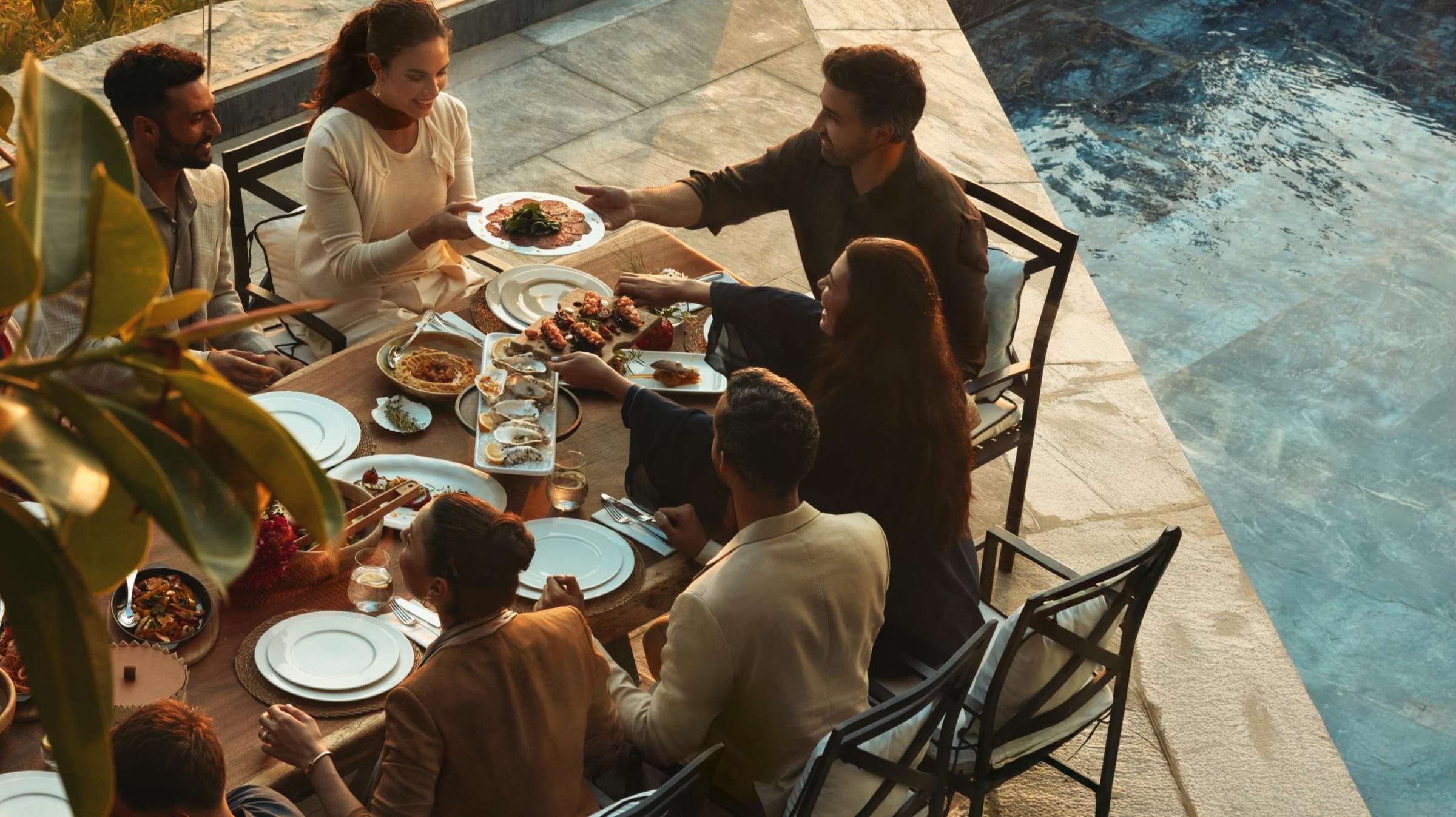Eine Familie beim gemeinsamen Essen auf einer Terrasse am Pool in Marsa Al Saadiyat