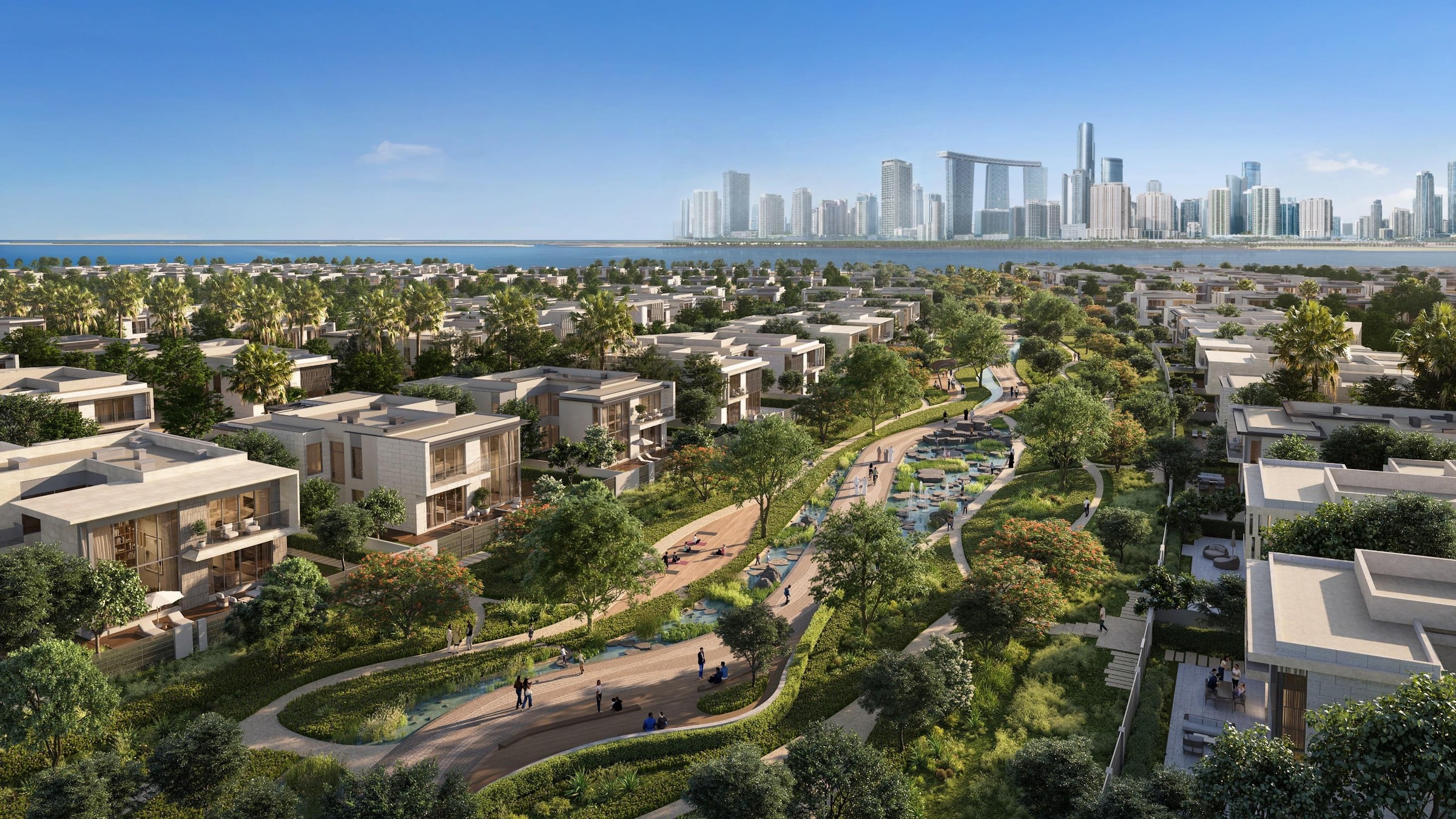 Flache Wohnhäuser in Marsa Al Saadiyat entlang eines begrünten Korridors, im Hintergrund die Skyline von Abu Dhabi