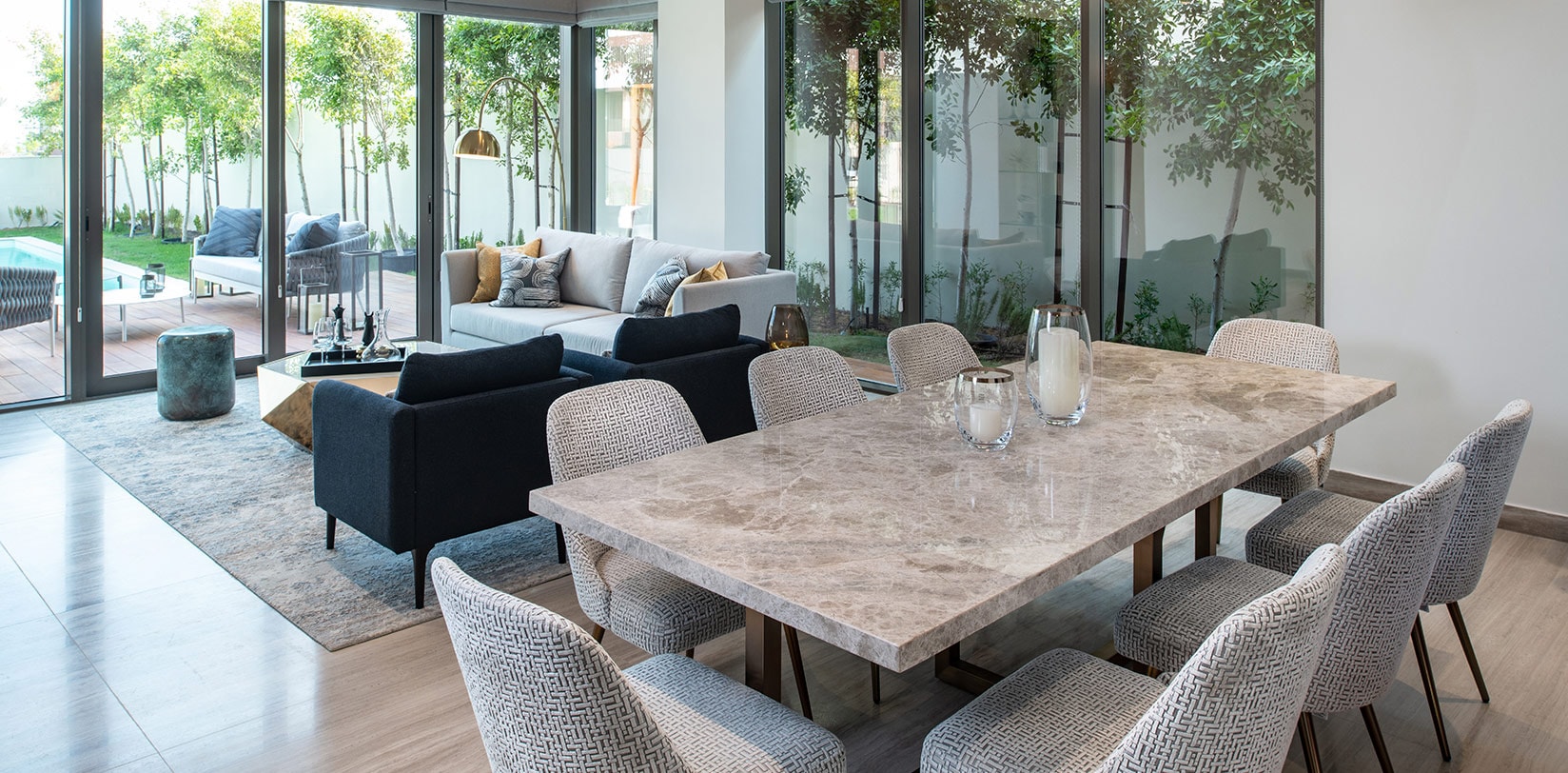 Photograph of a living and dining space at Nudra looking through full-height glazing to the private courtyard pool